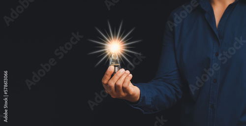 Creative new idea. Innovation, brainstorming, inspiration, and solution. The man is holding a light bulb while standing on a black background