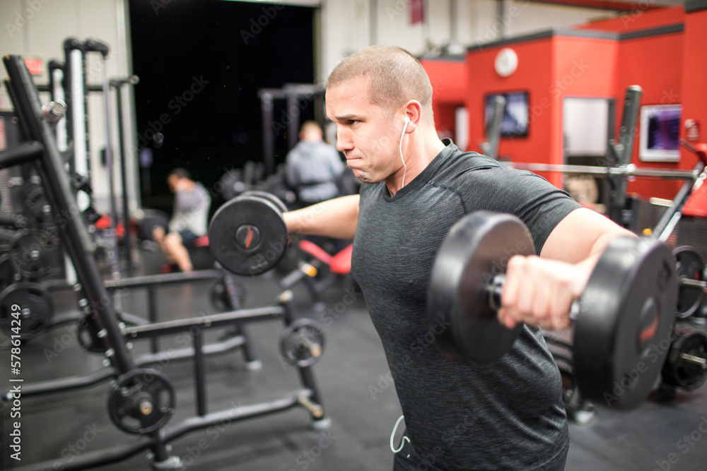 muscular man lifting free weights at the gym muscular man lifting free weights at the gym