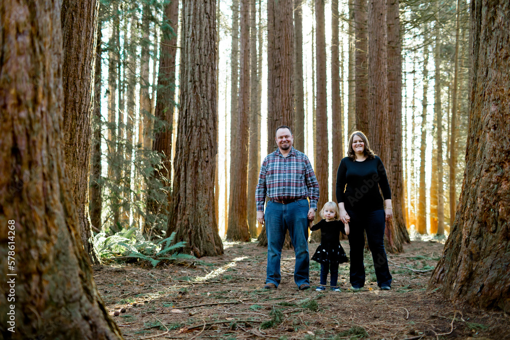 Mother and father with their toddler aged daughter stand in the forest Mother and father with their toddler aged daughter stand in the forest