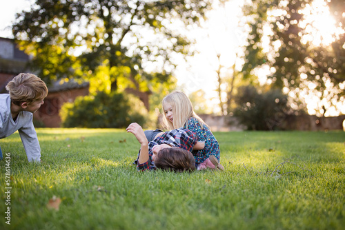 siblings playing and laughing in grassy field outdoors photo