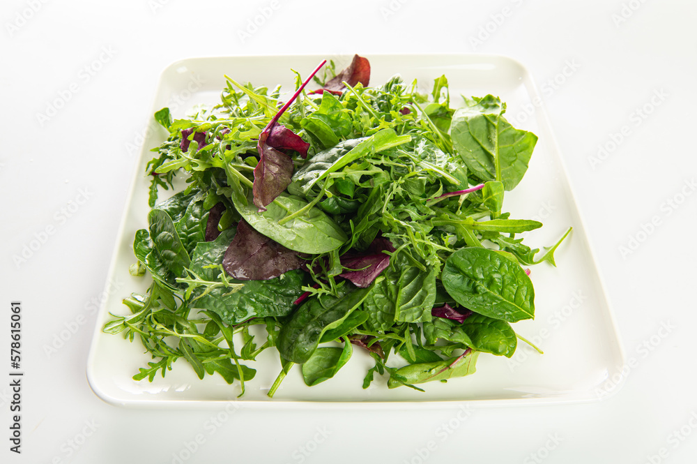 salad mix of fresh herbs, arugula, chard, spinach in a plate on a white plate, top-side view salad mix of fresh herbs, arugula, chard, spinach in a plate on a white plate, top-side view