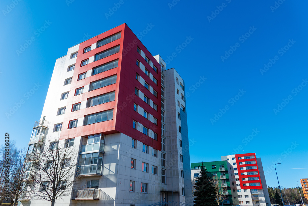A newly built building in nice bright colors with apartments for sale.Red orange and green block of flats.Newly finished modern style apartment building in freshly renovated residential area.
