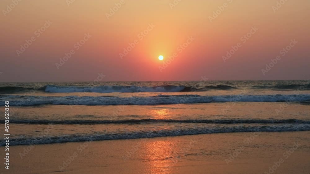 Beautiful sunset over the ocean. Foaming waves roll towards the shore against the setting sun on the horizon. Evening sky over the sea in a pink haze. 4K. Beautiful sunset over the ocean. Foaming waves roll towards the shore against the setting sun on the horizon. Evening sky over the sea in a pink haze. 4K.