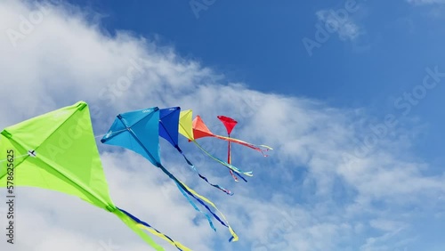Many beautiful colorful kites fly on the string over blue sky