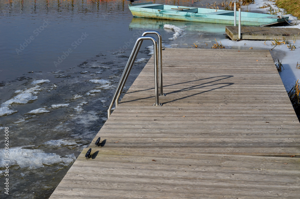 Naklejka premium frozen river has modified entrances to water from embankment. swimmer decides to take a bath as part of conditioning and hardening after sauna, it is possible to use stainless steel steps, ladder