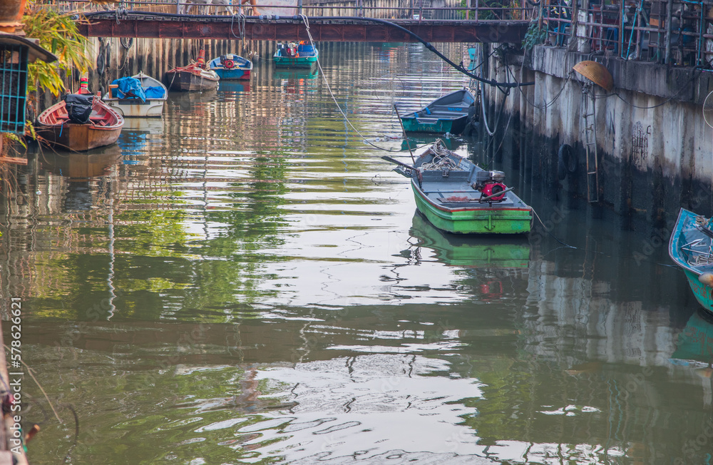 A klong or river channel with fishing boats, buildings and house fronts in Thailand Asia