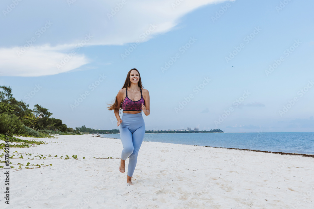 hispanic woman running at a beach in Mexico Latin America hispanic woman running at a beach in Mexico Latin America