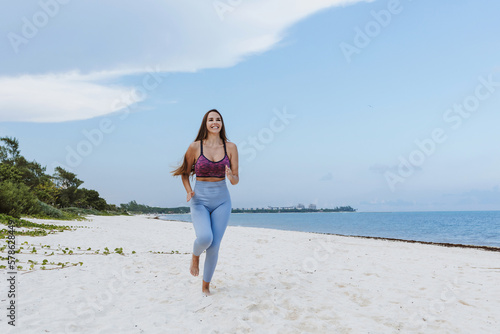 hispanic woman running at a beach in Mexico Latin America