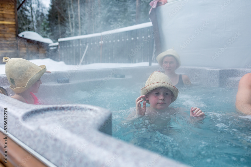 Cheerful happy family with children enjoys hot bath in jacuzzi