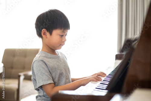 Asian young musician boy kid having fun activities play piano music lesson in music education at home