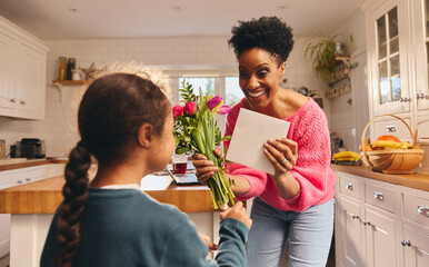 Boy giving mother bouquet and card on Mothering Sunday or Birthday