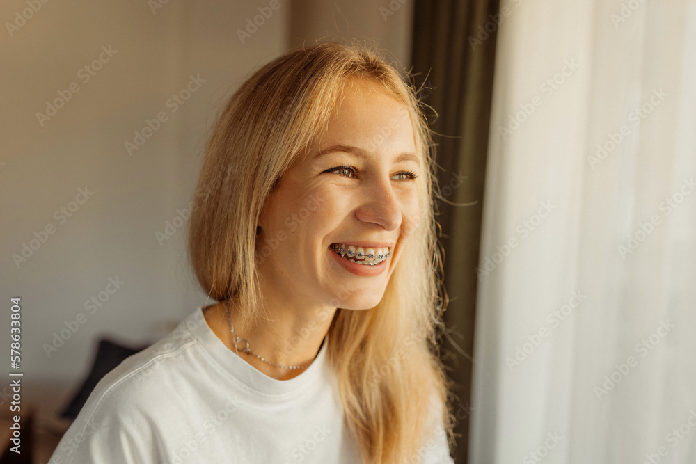 Happy laughing young woman in braces looking at window, warm positive photo Happy laughing young woman in braces looking at window, warm positive photo