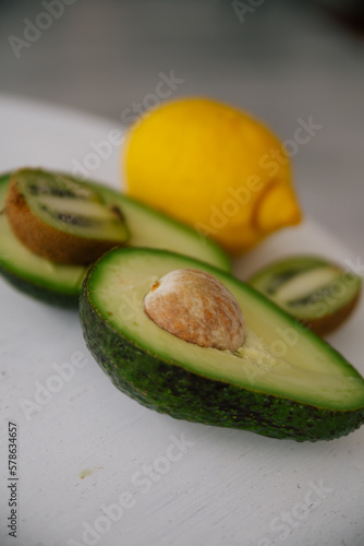 Cut in half avocado and kiwi, lemon isolated green on a table. Healthy eating food fruit organic fresh