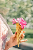 Flowers in a waffle cone in a woman's hand. The flowering of fruit trees in the garden.