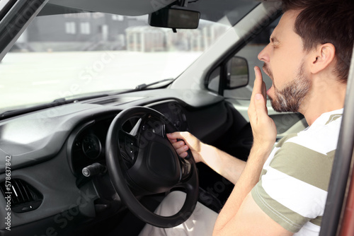 Sleepy man yawning while driving his car