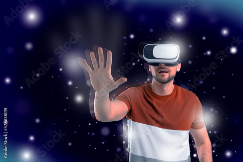 Innovation idea. Man exploring space using VR headset. Lights and blue gradient background as cosmos around him symbolizing digital reality