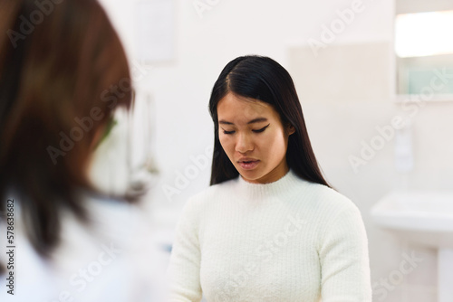 Asian upset woman listening to her doctor talking about an illness at the clinic.
