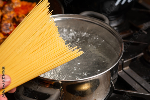 Dip spaghetti into boiling water in a saucepan. Pasta cooking.