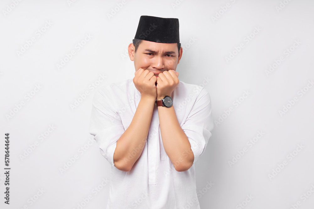 Anxiety problem. Portrait of afraid young Asian Muslim man in Arabic clothes looking stressed and nervous with hand on mouth isolated on white background. People religious Islamic lifestyle concept Anxiety problem. Portrait of afraid young Asian Muslim man in Arabic clothes looking stressed and nervous with hand on mouth isolated on white background. People religious Islamic lifestyle concept