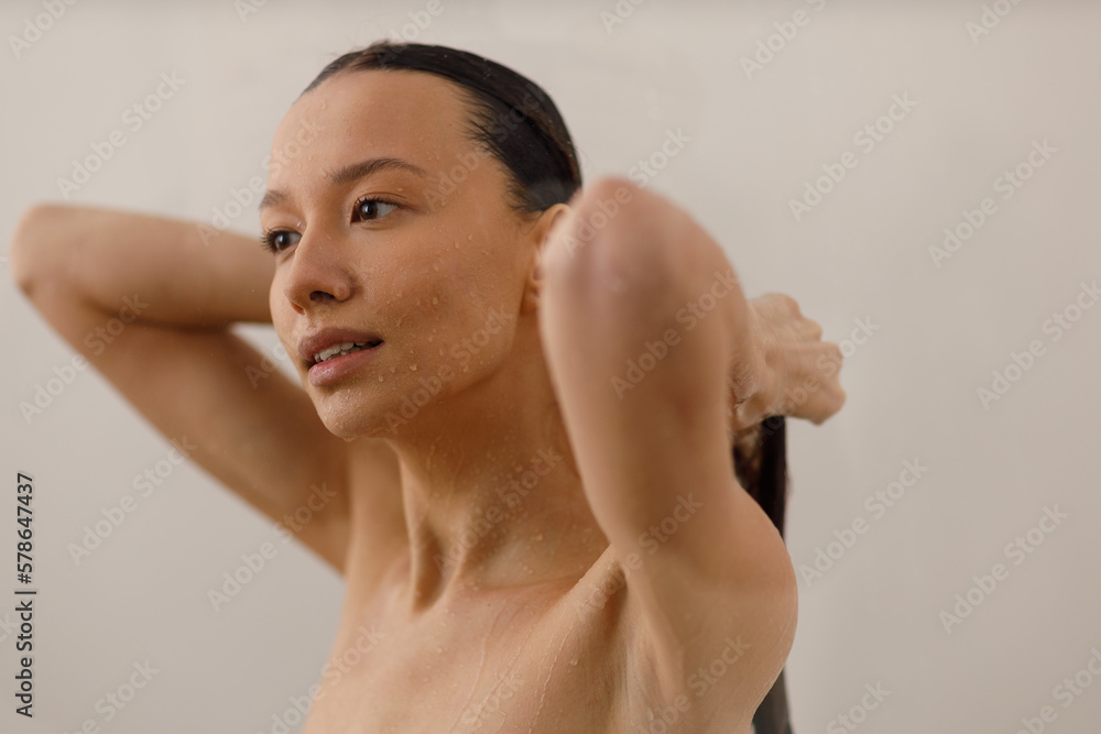 Obraz premium Young woman under the trickles of water in pleasure shower. Beautiful girl under the spray of water. Wet happy face