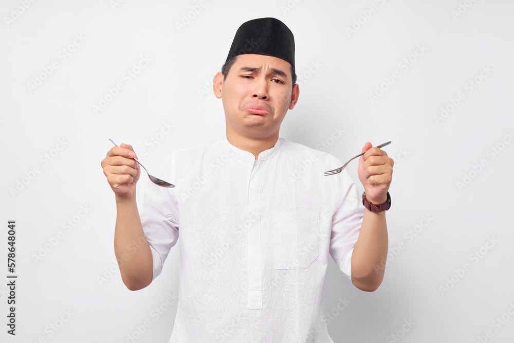 Feeling Hungry young Asian Muslim man in Arabic clothes hold spoon and