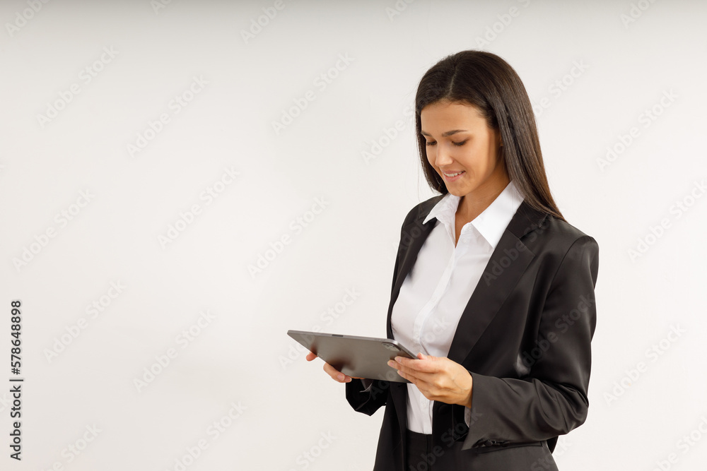 Portrait of successful business woman with tablet in her hands, dressed in white shirt and black jacket on isolated white background. Studio shot of attractive brunette girl looking into the camera. Portrait of successful business woman with tablet in her hands, dressed in white shirt and black jacket on isolated white background. Studio shot of attractive brunette girl looking into the camera.