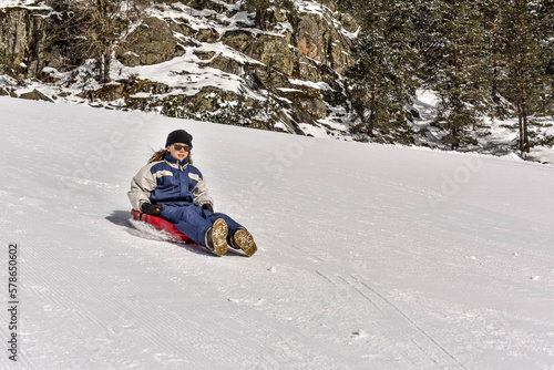 Pretty young girl sledding in a beautiful scenery of the snowy mountains