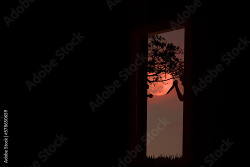 Silhouette of scary man holding knife at door in red moon night © Warawut