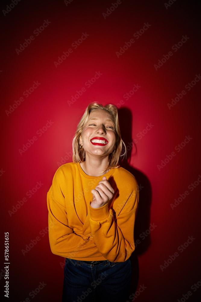 A happy woman standing in front of the red background and laughing. Cheerful woman is laughing while standing on isolated red background. A happy woman standing in front of the red background and laughing. Cheerful woman is laughing while standing on isolated red background.