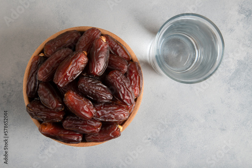 Glass of water with a bowl of date fruit on bright background photo