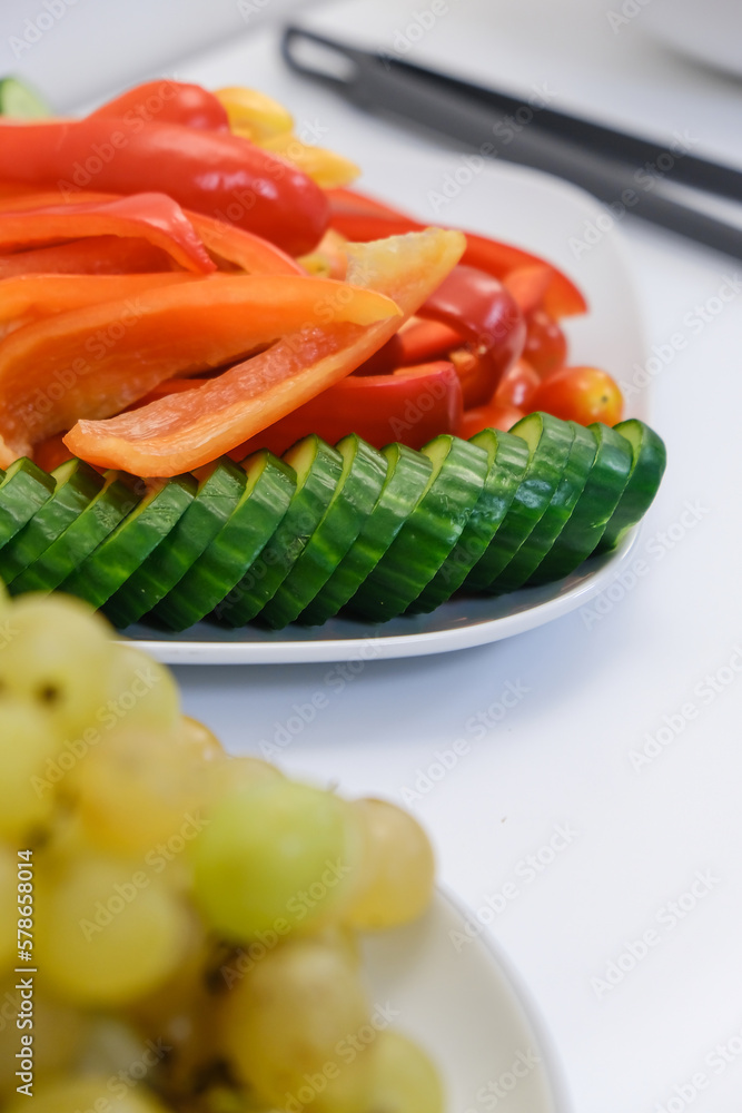 White plate with cucumbers and tomatoes on white background. Vegetarian food. Natural background. Organic food. Vertical image. White plate with cucumbers and tomatoes on white background. Vegetarian food. Natural background. Organic food. Vertical image.