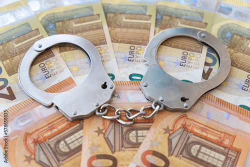 Photos metal handcuffs against the background of the cash currency european EUR
