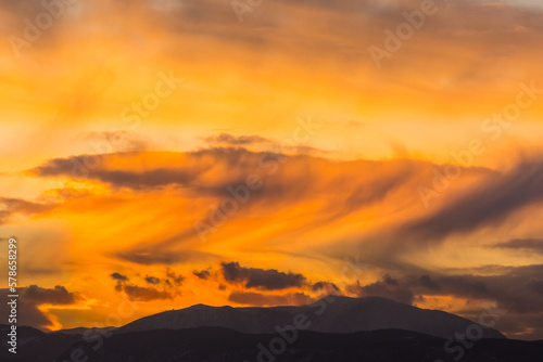 amazing clouds with storm during sundown in a flat landscape with a moutain