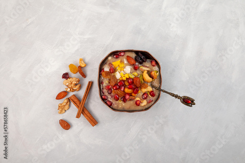 Ashure Dessert, Ashura or Anusabur in metal bowl on grey background, top view. Turkish pudding also called as Noah's pudding or Noah's Dessert. Sweet porridge with grains, fruits, and nuts photo