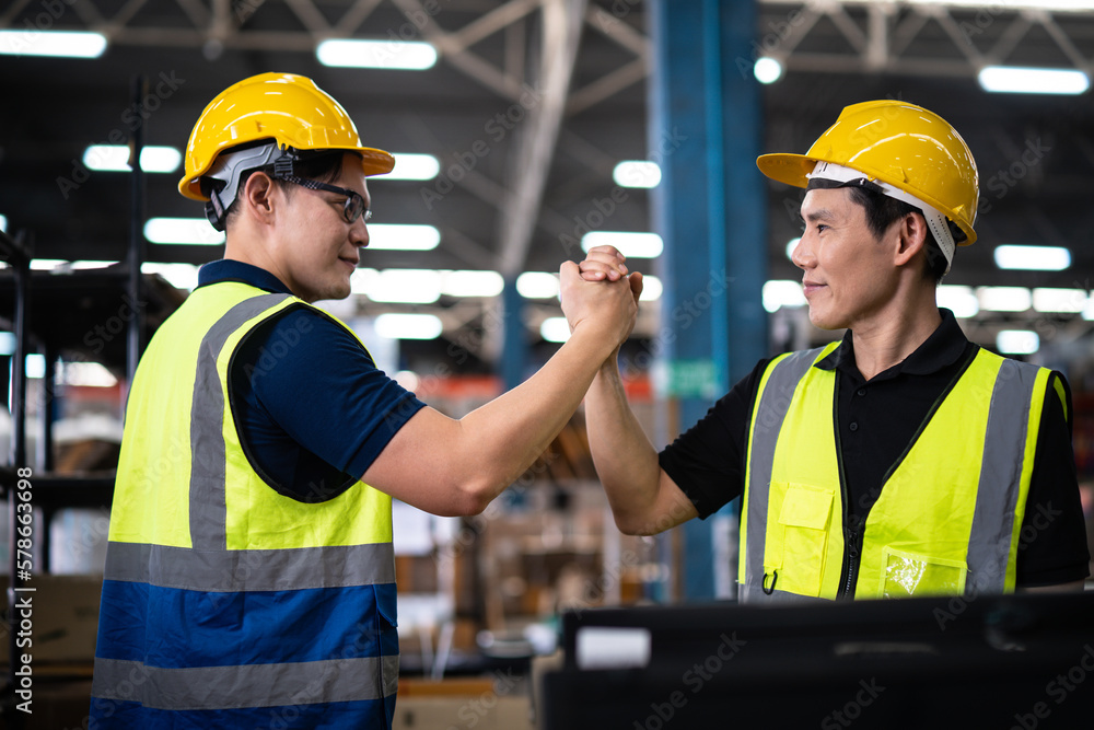 Two Asian warehouse workers showing teamwork and partnership. teamwork at warehouse storage department. Two Asian warehouse workers showing teamwork and partnership. teamwork at warehouse storage department.