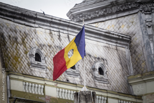 Romanian revolutionary flag with a hole, also called Drapelul Romaniei waiving on a flagpole of Timisoara. It is the national symbol of Romania, emblem of the 1989 romanian revolution ending up Commun photo