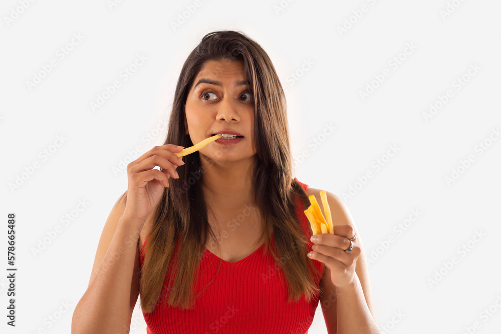 Close-up portrait of woman eating french fries against white background Close-up portrait of woman eating french fries against white background