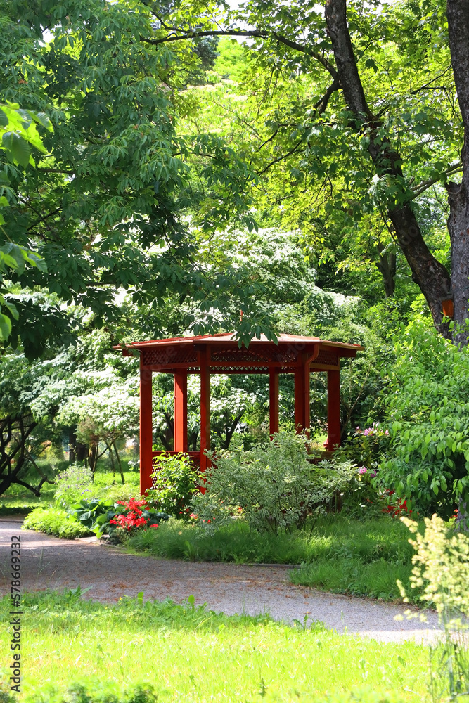 Red pavilion and lush green trees in the park. Red pavilion and lush green trees in the park.