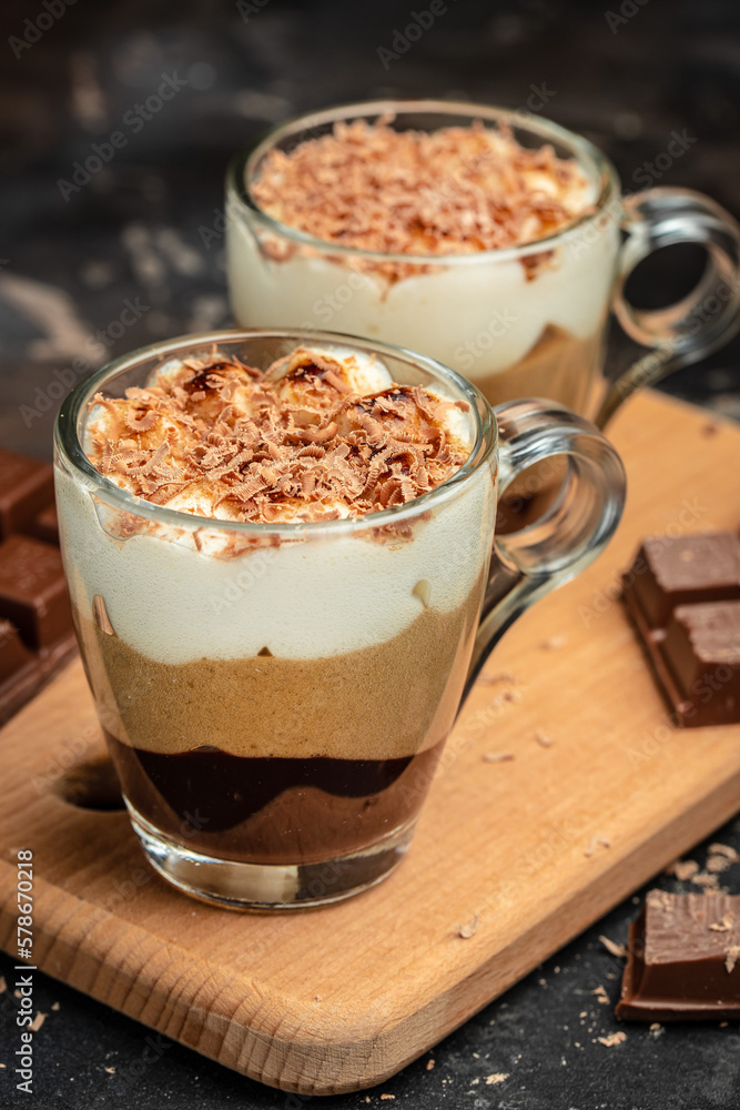 Dessert with three layers chocolates mousse, vanilla, chocolate, creme brulee dessert on a dark background. place for text, top view Dessert with three layers chocolates mousse, vanilla, chocolate, creme brulee dessert on a dark background. place for text, top view