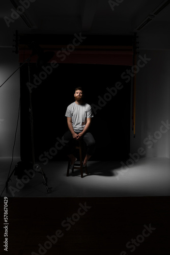 Handsome a brunette brutal bearded man in a grey t-shirt on studio photo session. Stylish and handsome man with a beard.