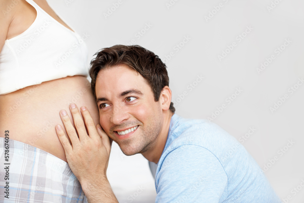 Getting close to his baby - Copyspace. Happy father with his ear next to his wifes pregnant belly. Getting close to his baby - Copyspace. Happy father with his ear next to his wifes pregnant belly.