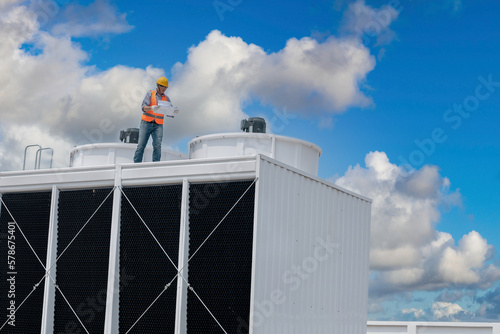 Industry engineer under checking the industry cooling tower air conditioner is water cooling tower air chiller HVAC of large industrial building to control air system.