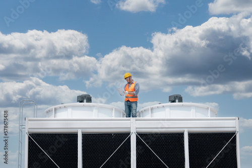 Industry engineer under checking the industry cooling tower air conditioner is water cooling tower air chiller HVAC of large industrial building to control air system. photo