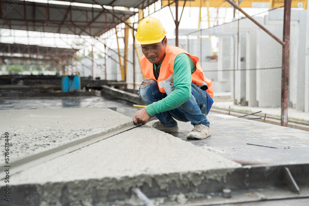 Construction technician working by leveling concrete floor to smooth. Construction worker uses long trowel spreading wet concrete pouring at construction site. Mason making smooth surface of concrete