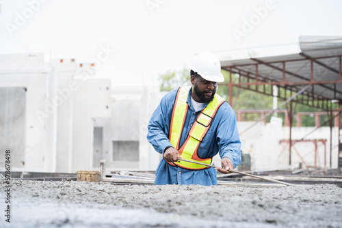 Foto Construction worker uses long steel trowel spreading wet concrete pouring at precast concrete wall construction site