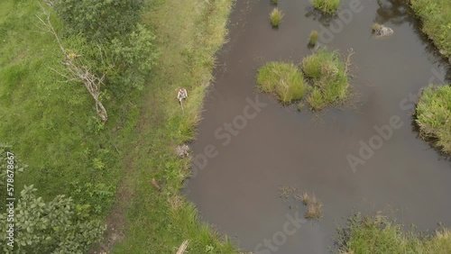 Man cutting grass by lagoon. Aerial yop view photo
