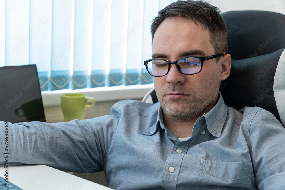 Young businessman in blue shirt sleeping on desk in office Young businessman in blue shirt sleeping on desk in office
