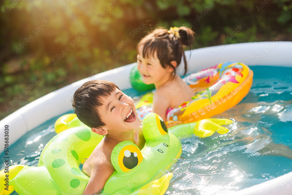 Family vacation in an inflatable pool in summer. Children swim on inflatable circles. - obrazy, fototapety, plakaty 