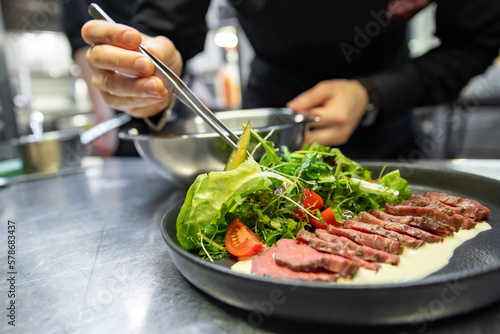 chef hand preparing Roastbeef salad with vegetables on restaurant kitchen
