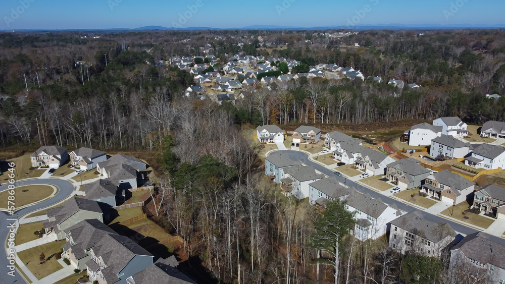 Obraz premium Planned settlement suburban area with Chestnut Mountain background and row of new developments houses, traffic circle (roundabout), cul-de-sac, lush green trees, Georgia, US